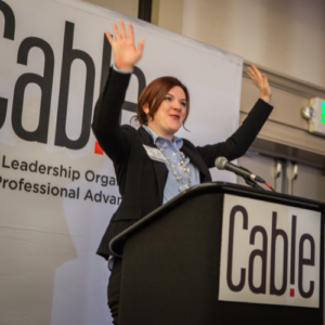 Anna-Vija McClain as a speaker addressing audience from a lectern for Cable