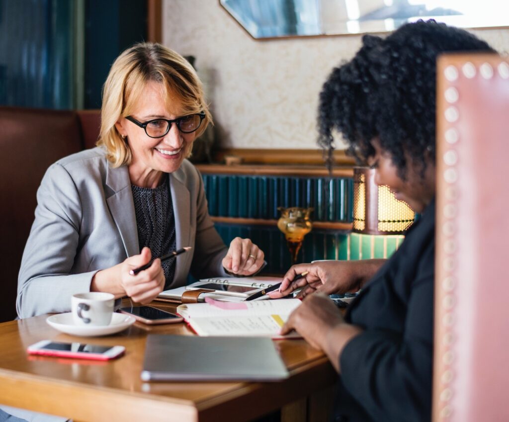 Two professionals engaged in a collaborative discussion over documents at a cozy cafe, with coffee to fuel their productivity.