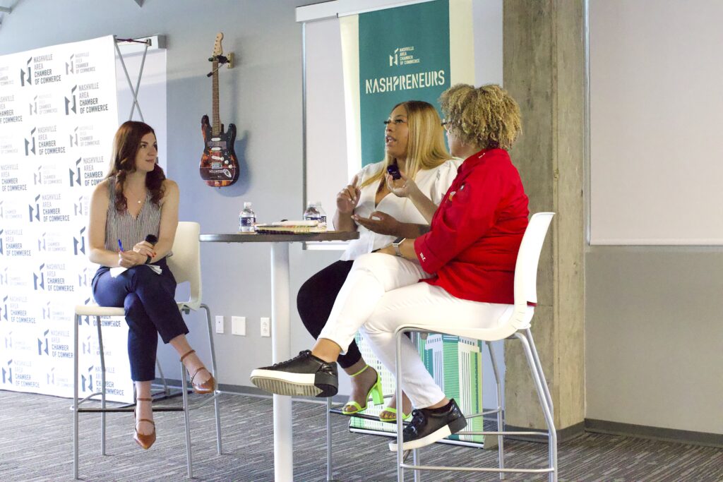 Three individuals engaged in a panel discussion at a corporate or conference event.